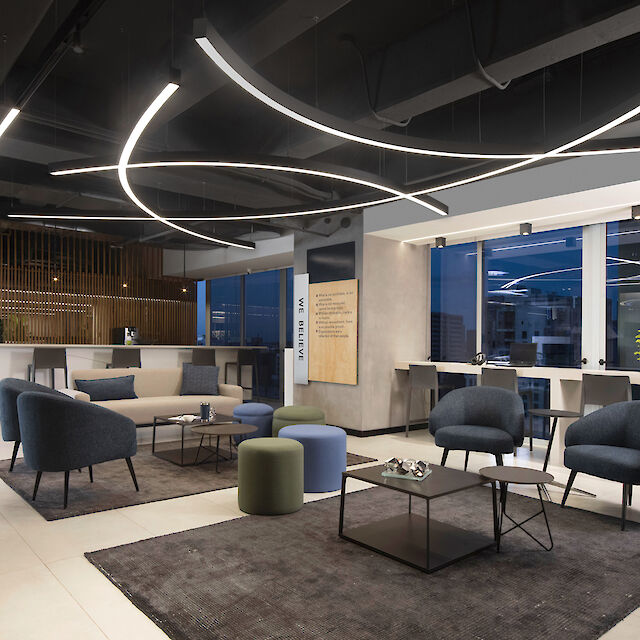 Moderne Büro-Lounge mit stilvollen Sitzgruppen und gebogenen LED-Licht an der Decke. Die Einrichtung umfasst blaue und graue Sessel sowie eine minimalistische Dekoration.
