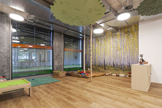 Play area with birch-look wall mural, round basic pendant luminaires and nature-inspired ceiling elements.