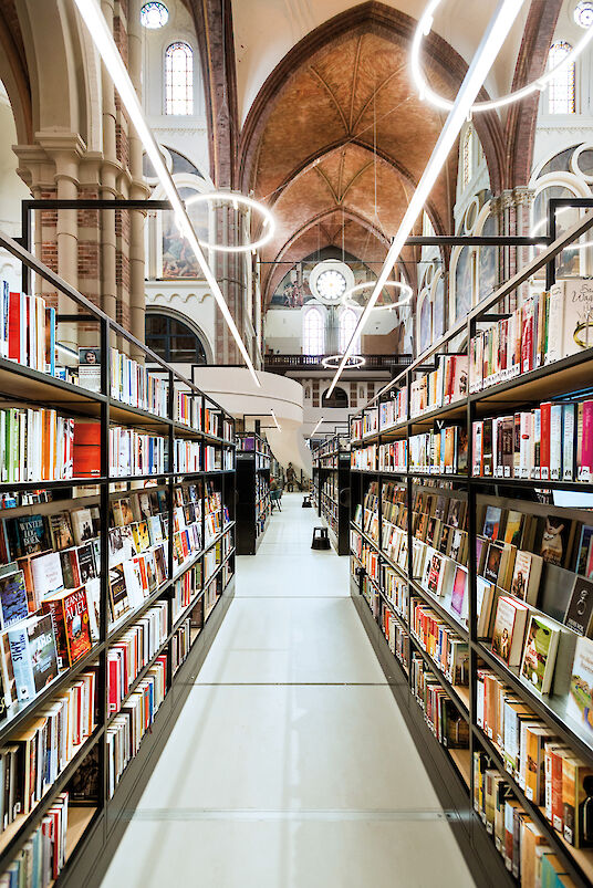 Bücherregale in historischer Kirche mit ringförmigen Ringo Star Pendelleuchten.