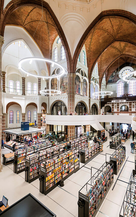 Bibliothek in ehemaliger Kirche mit Bücherregalen und ringförmigen Ringo Star Pendelleuchten.