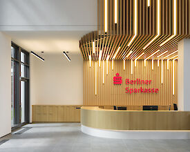 Modernes Bankfoyer der Berliner Sparkasse mit Holzlamellen-Decke und integrierten LED-Leuchten