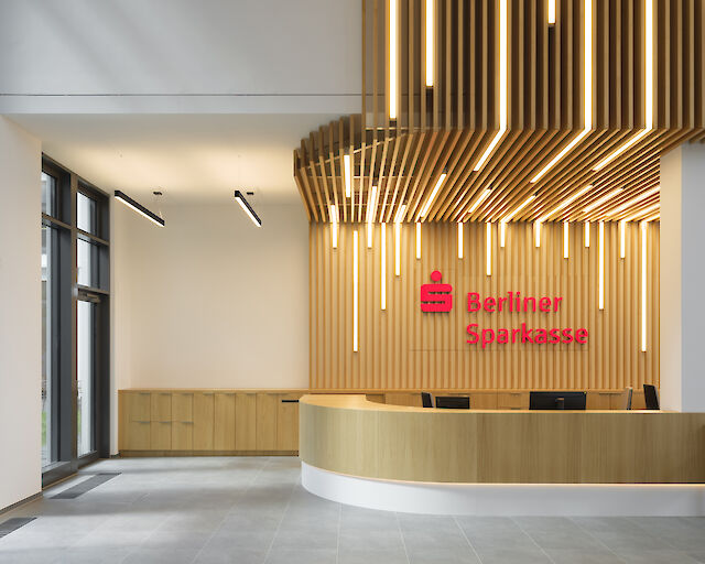 Modernes Bankfoyer der Berliner Sparkasse mit Holzlamellen-Decke und integrierten LED-Leuchten
