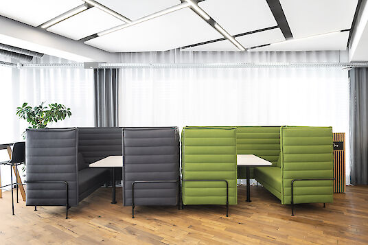 Cantina con mobiliario tapizado en verde y gris y luminarias Matric lineales con luz diurna.