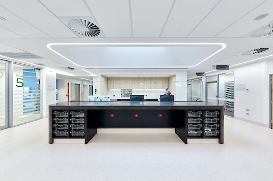Service hospitalier lumineux avec comptoir d'accueil central noir, lignes lumineuses Liquid Line.