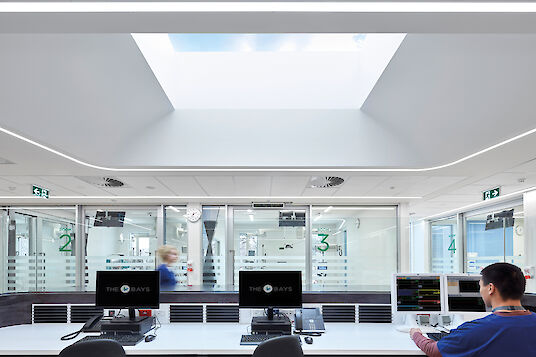 Service hospitalier avec lanterneau, lignes lumineuses Liquid Line et vue sur plusieurs chambres de patients.
