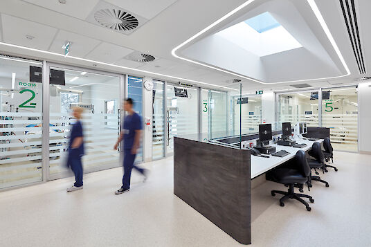 Service hospitalier avec lanterneau, lignes lumineuses Liquid Line, postes de travail et personnel soignant de passage.