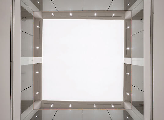 Vista hacia arriba de un atrio con un gran campo de luz y focos de techo «Midpoint».