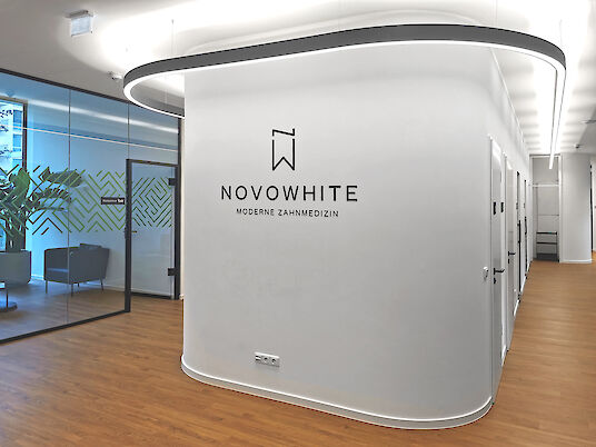 Reception area of the dental practice with curved wall, logo and curved Liquid Line pendant luminaire.