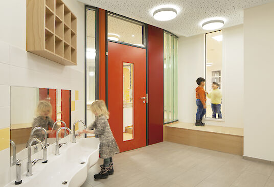 Salle de bain pour enfants avec des portes rouges, un lavabo à hauteur d'enfant et des luminaires Basic ronds en saillie au plafond.