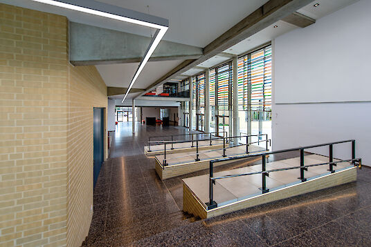 Entrance area with ramps, colourful façade elements and linear Matric pendant luminaires.