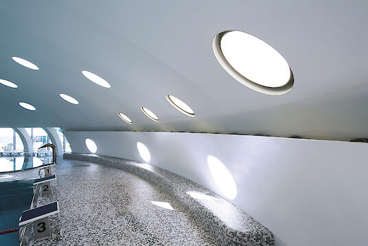 Starting blocks at the edge of the pool, curved ceiling with round Basic surface-mounted luminaires and reflective light surfaces.