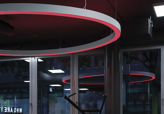 Detailed view of a red Ringo Star pendant luminaires in front of a window in a fitness studio.
