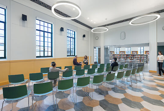 Bright event room in library with ring pendant lights, green chairs and hexagonal floor