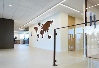 Entrance area with world map on the wall and linear ceiling lighting in the renovated Apageo headquarters