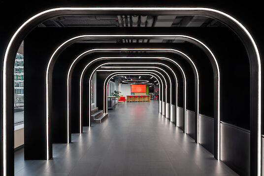 Light-dramatised corridor with black arches and integrated LED lighting, view towards lounge area.