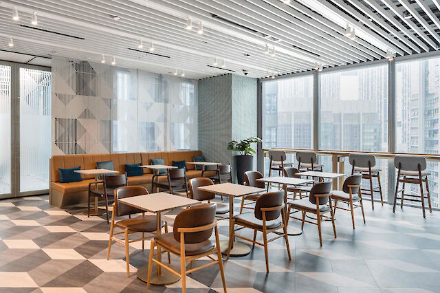 Modern lounge area with geometric flooring, wooden furniture, and large windows.