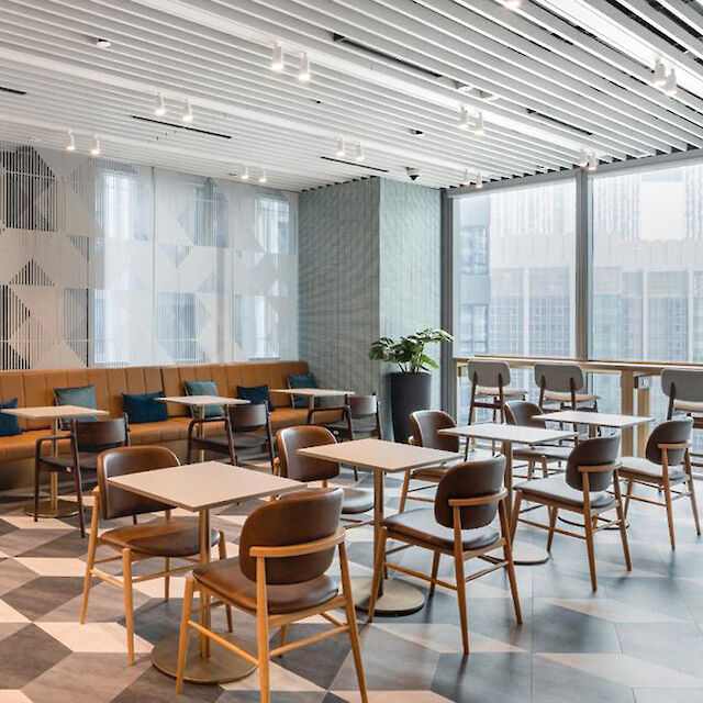 Modern lounge area with geometric flooring, wooden furniture and large windows.