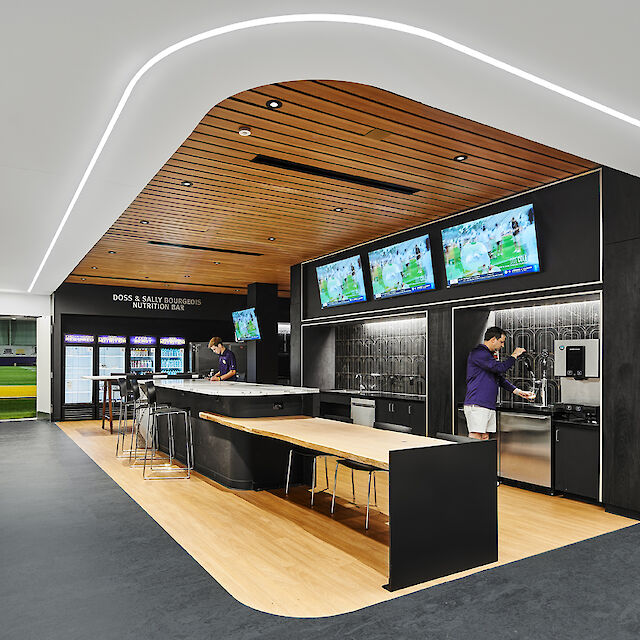 Modern nutrition bar with wooden ceiling, LED strip lighting, screens and beverage station