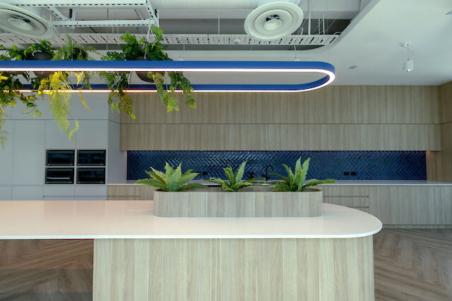 Blue Liquid Line pendant light above kitchen island with plants, wooden fronts and blue tiled backsplash