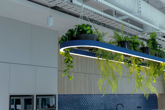 Lámpara colgante Liquid Line azul con plantas integradas, cocina moderna con frentes de madera y pared de azulejos azules