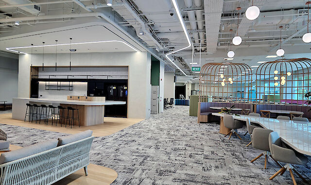 Modern office with lounge, open kitchen, meeting areas, and curved light lines on the ceiling