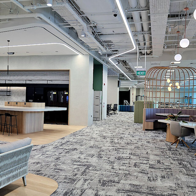 Moderna oficina con sala de estar, cocina abierta, zonas de reunión y líneas de luz curvas en el techo