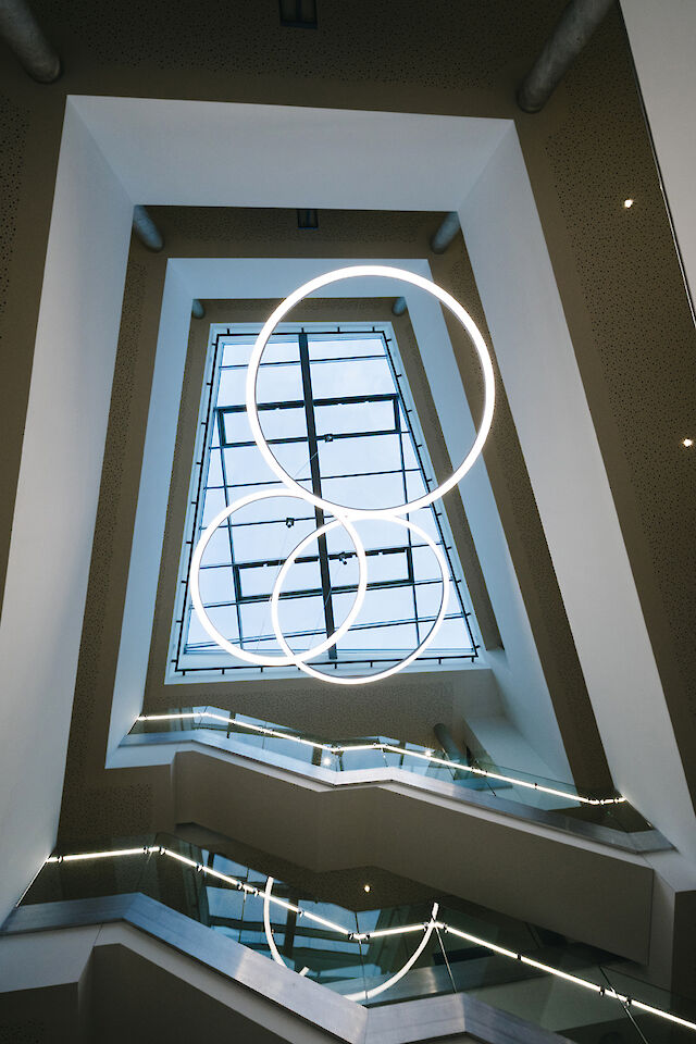 Drei Ringo Star LED-Pendelleuchten von Lightnet beleuchten das moderne Treppenhaus im Rathaus Delbrück