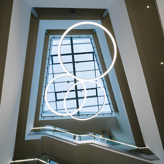 Three Ringo Star LED pendant lights from Lightnet illuminate the modern stairwell in Delbrück Town Hall
