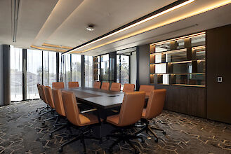 Moderna sala de conferencias con una gran mesa, sillas de cuero y lámpara colgante Matric de Lightnet sobre la mesa