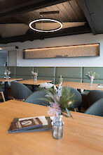 Round Ringo Star light circle above wooden tables and upholstered bench in a tranquil restaurant setting