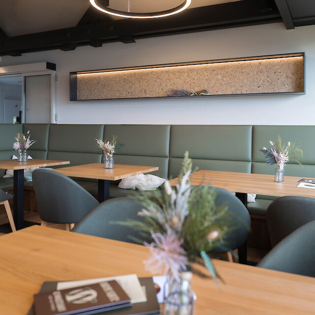 Round Ringo Star light circle above wooden tables and upholstered bench in a tranquil restaurant setting