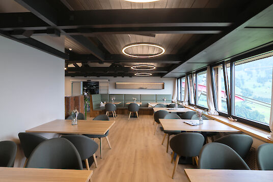 Spacious restaurant interior with round Ringo Star pendant lights, wooden furniture and sweeping views of the valley