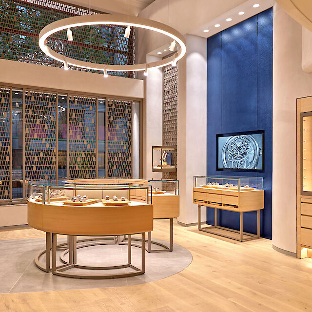 Bright watch boutique with round display cases, Ringo Star pendant light, Midpoint spotlights and wooden surfaces