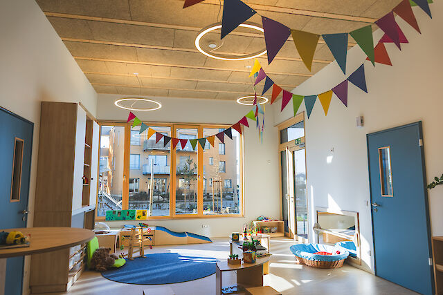 Heller Kindergartenraum mit bunten Wimpeln, Spielzeug, großen Fenstern, inspiriert von Ringo Star