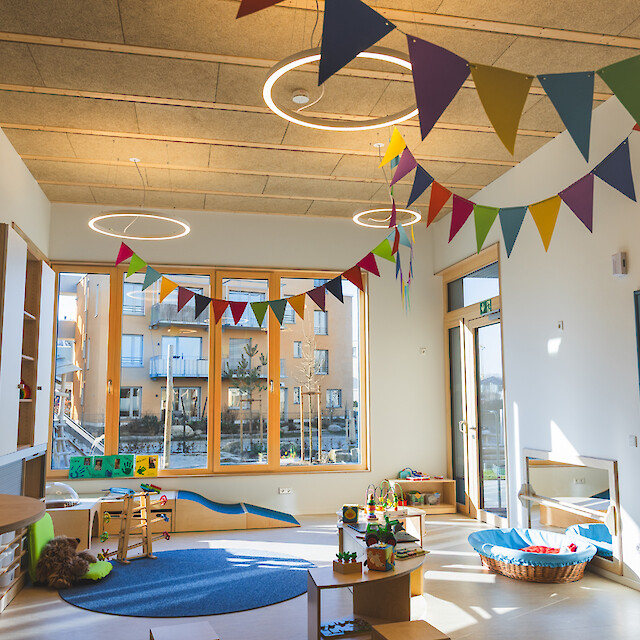 Heller Kindergartenraum mit bunten Wimpeln, Spielzeug, großen Fenstern, inspiriert von Ringo Star