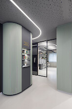 Ligne liquide sinueuse sur plafond perforé, murs vert sauge, couloir moderne avec cloison vitrée