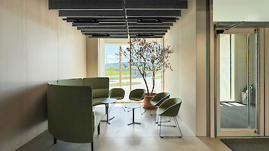 Espace lounge avec coin salon, lumière naturelle et éclairage linéaire au plafond grâce à Liquid Line-CX