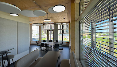 Salle de réunion avec plafond à poutres apparentes, suspensions rondes Basic Neo P5 et lumière du jour