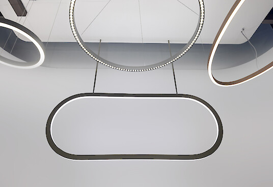 Hängende, ovale Lichtleuchte mit gleichmäßigem Lichtband, umgeben von weiteren ringförmigen Leuchten