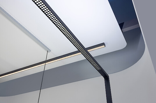 Lineare Stehleuchten mit Mikrostruktur vor moderner Decke, klare Formen und reduzierte Architektur
