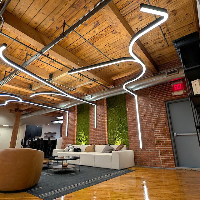 Lounge area with brick walls, a wooden beam ceiling, and curved lighting fixtures running from the wall to the ceiling