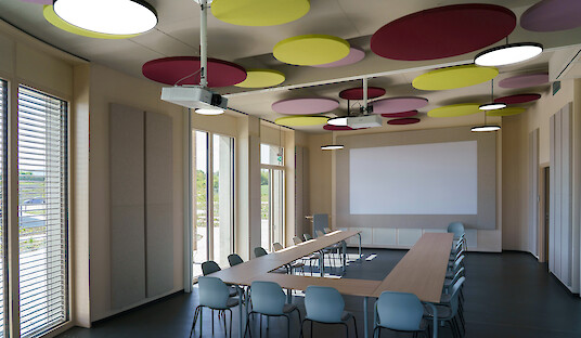 Salle de séminaire avec éléments acoustiques colorés et suspensions rondes Basic Neo P5