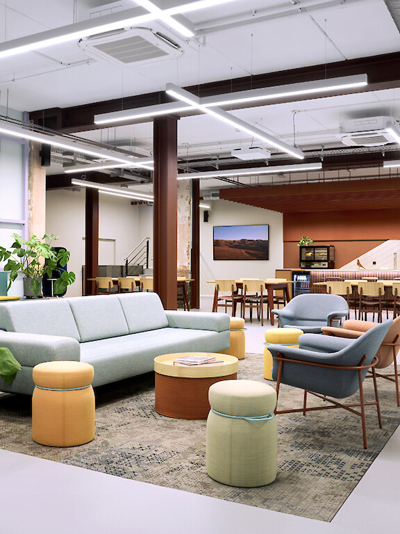 Open office area with lounge seating, plants and linear lighting.