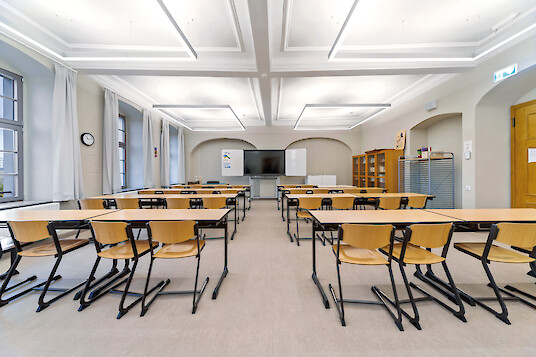 Classroom with linear lighting, tables and chairs.