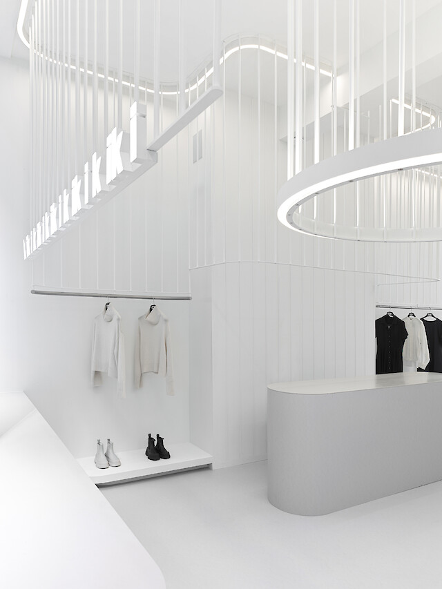 Boutique mit organisch geschwungenen Lichtlinien und runden Leuchten in ruhiger Raumkomposition