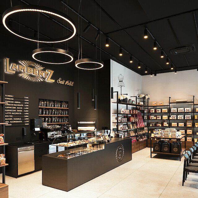 Espacio comercial con cafetería integrada, barra, vitrina de pasteles y zona de descanso