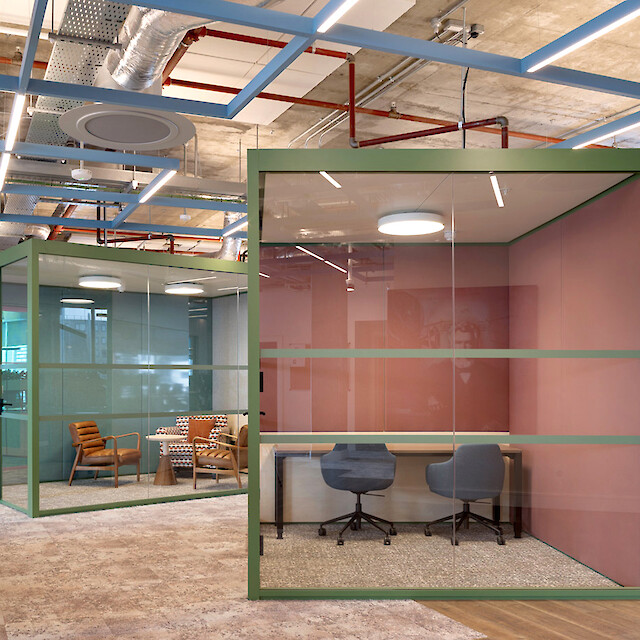 Espace de bureau moderne avec cabines de réunion vitrées, installations apparentes au plafond