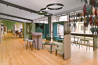 Open space with meeting areas, organic pendant lights, hardwood floors, and floor-to-ceiling windows