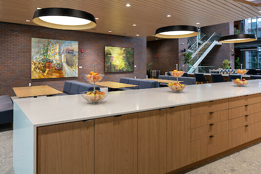 A spacious dining room with a kitchen island, round pendant lights, and seating areas set against brick walls
