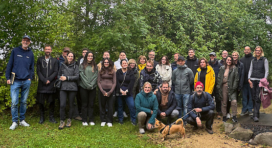 Group of people with a dog during a visit in a wooded setting.